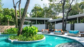 Una piscina de diseño circular, rodeada de sillones de descanso y una zona de estar cubierta.