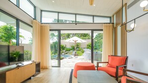 Una sala de estar moderna con un televisor de pantalla plana, muebles de madera y vistas a un patio trasero con piscina.