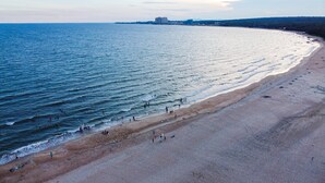 Una playa con gente nadando y caminando por la orilla.