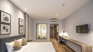 Una habitación de hotel moderna con una cama grande, un escritorio, un televisor y obras de arte enmarcadas en las paredes.
