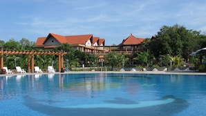 Un resort con una amplia piscina, varias edificaciones con tejados rojos y exuberante vegetación.