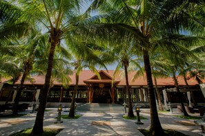 A resort with a central building, palm trees, and a paved walkway.