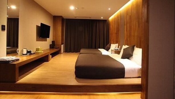A modern hotel room with a large bed, a wooden bench, a flat-screen TV, and a large mirror. - Designers Hotel The Rich (Goyang)