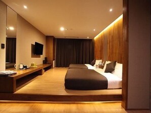 A modern hotel room with a large bed, a wooden bench, a flat-screen TV, and a large mirror. - Designers Hotel The Rich (Goyang)