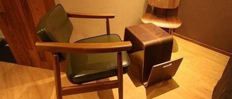 A modern room with a wooden floor, a green chair, and a wooden cabinet.