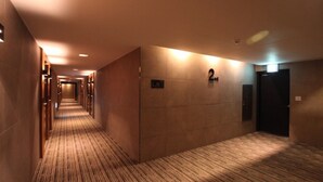 A hotel corridor with a carpeted floor, wooden doors, and a number sign indicating room 204. - Designers Hotel The Rich (Goyang)