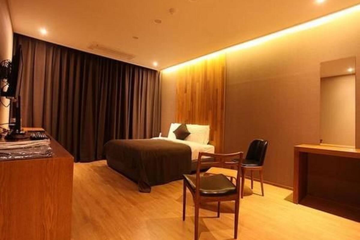 A hotel room with a bed, a desk, and a chair.