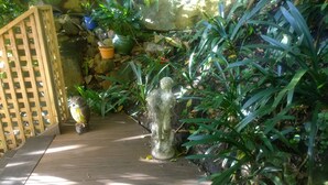 A wooden pathway leading through a garden with various plants and a statue of a figure. - Linley House (Linley Point)