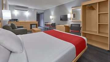 Una habitación de hotel con cama, escritorio, silla, armario y televisor.