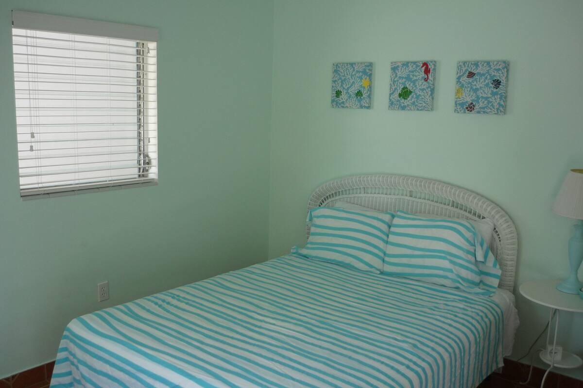 A bedroom with a bed, a window, and three wall art pieces.