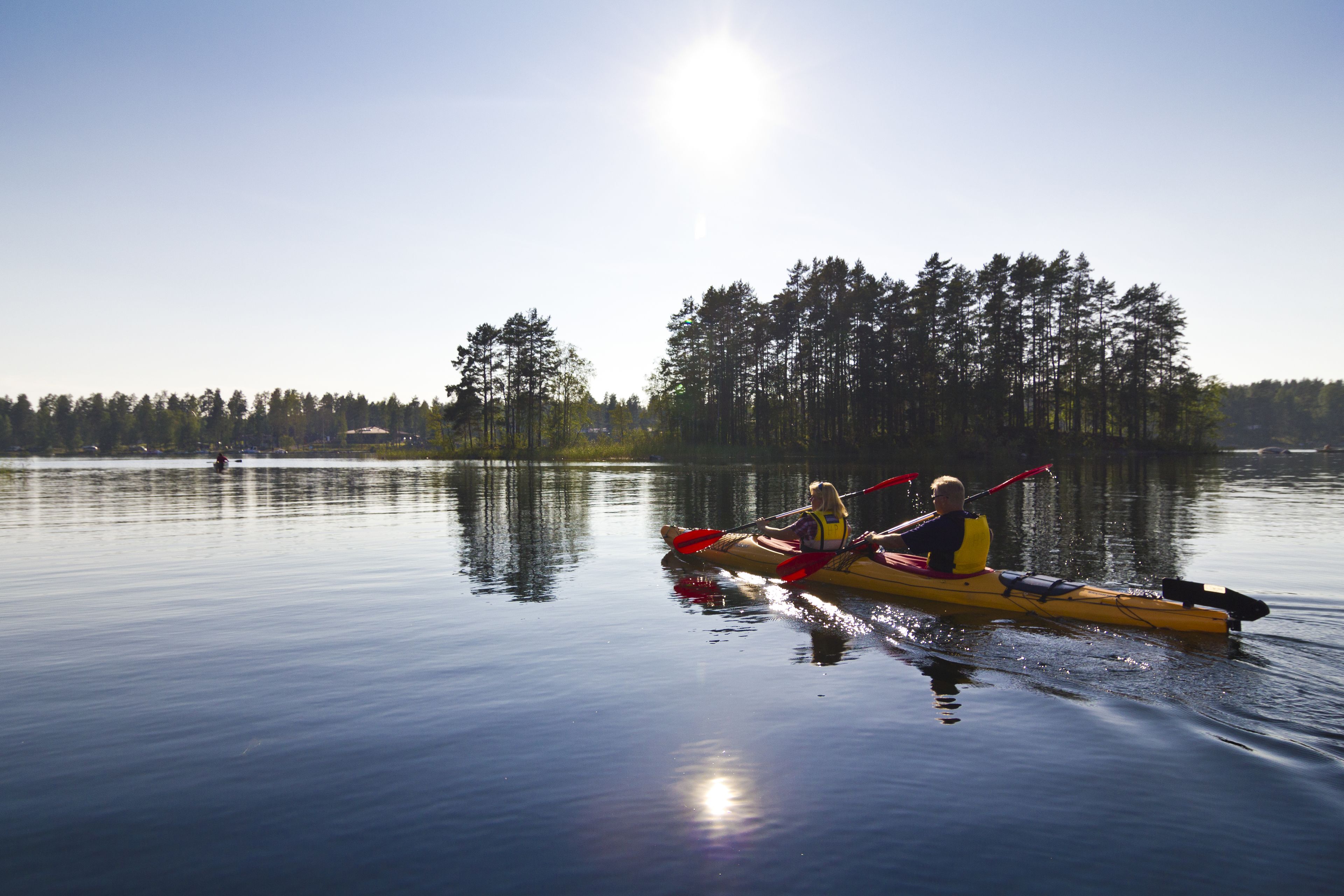 A calm lake with a kayak and two paddlers.