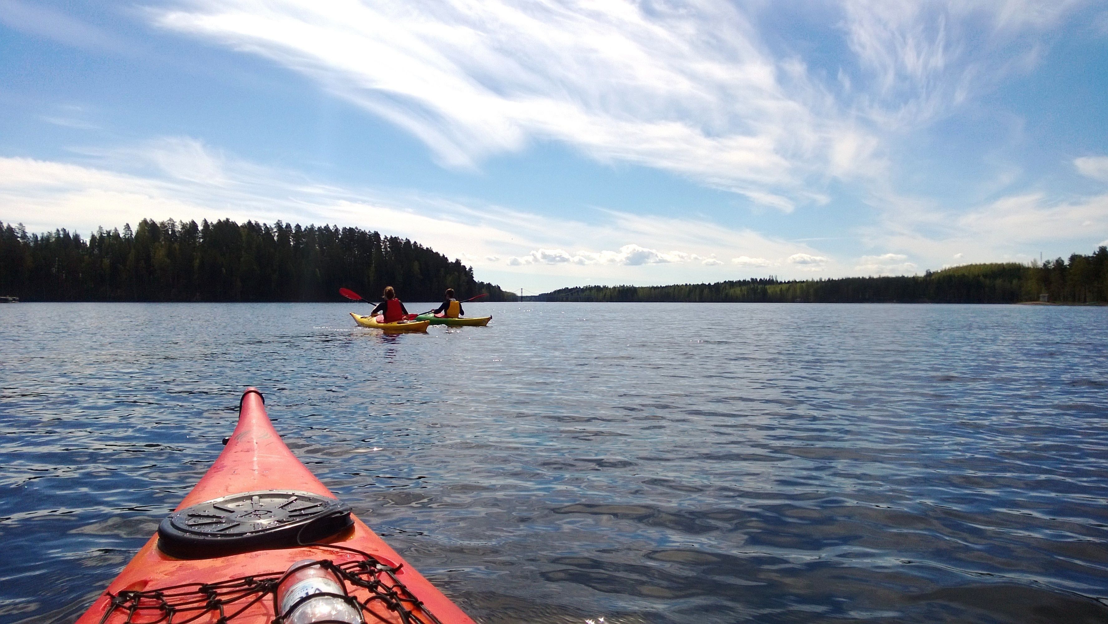 A kayak on calm water with a forested shoreline in the background.