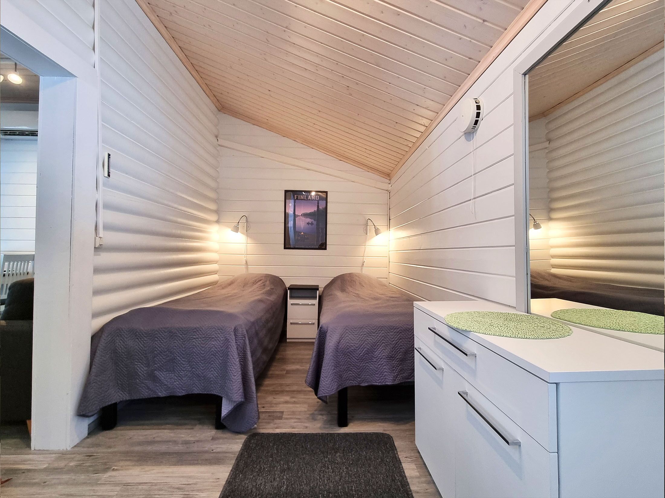 Habitación pequeña con dos camas, un escritorio y un espejo.