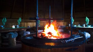 A circular fire pit with a metal grate and a central fire. - Holiday Resort Harjun Portti (Savonlinna)