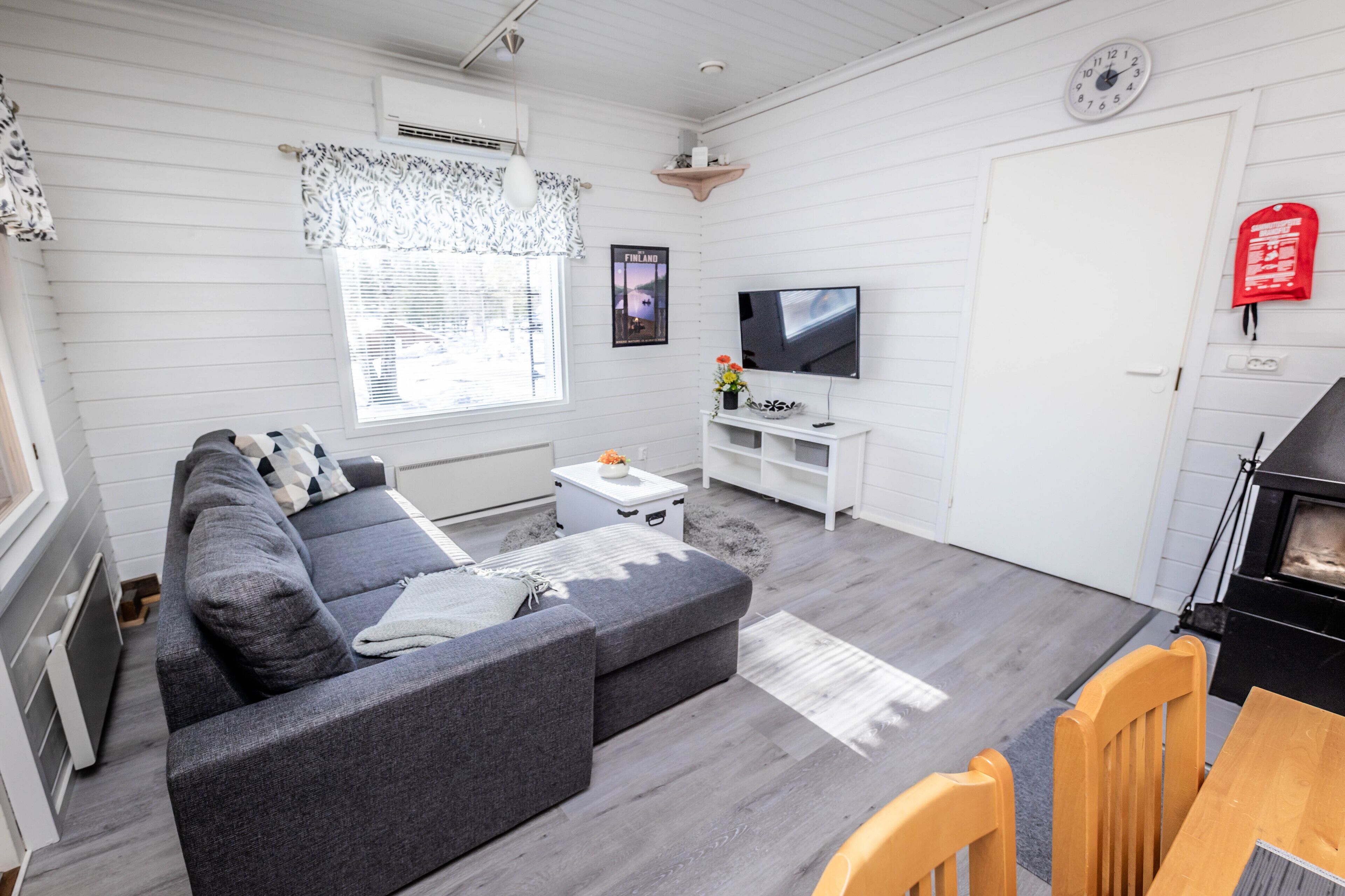 A modern living room with a grey sectional sofa, a TV, a fireplace, and a dining area with a wooden table and chairs.
