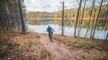 Un vététiste sur un sentier de terre, entouré d’arbres et bordé d’un lac.
