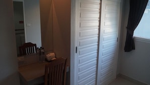 A bedroom with a bed, a bedside table, and a window with curtains. - P.F Mansion (Koh Samui)
