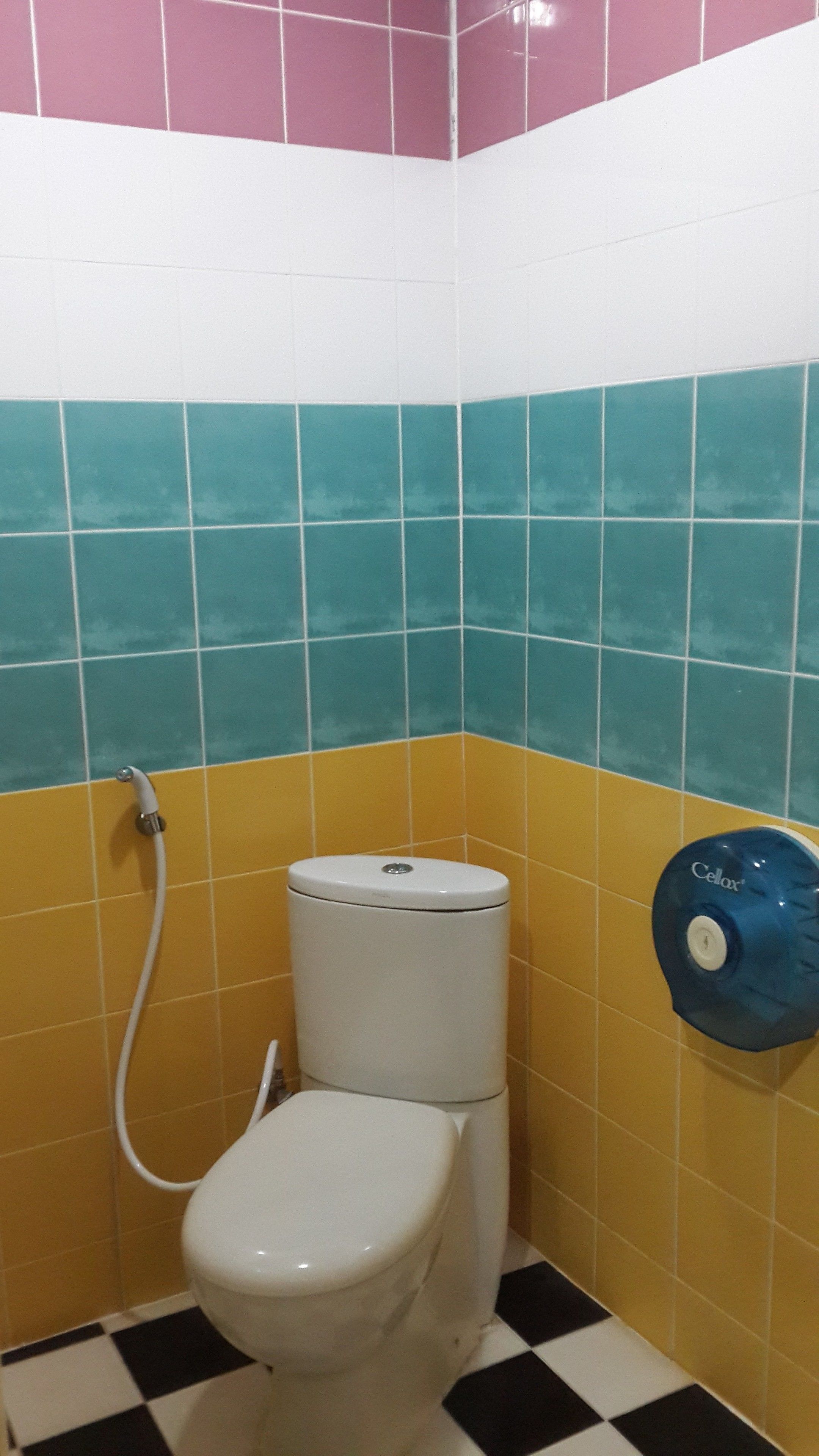 Un baño pequeño con inodoro, ducha manual y secador de manos.