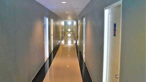 A long, narrow hallway with doors on both sides, leading to a brightly lit area at the end. - P.F Mansion (Koh Samui)
