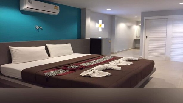 A modern hotel room with a large bed, a teal accent wall, an air conditioning unit, and a cross-shaped light fixture. - P.F Mansion (Koh Samui)