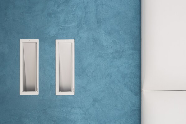 A blue textured wall with two white rectangular vents.