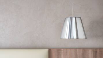 Een moderne hanglamp met metalen afwerking, hangend aan een plafond met een gestructureerde wand.