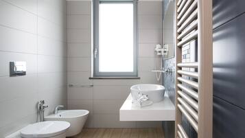 A modern bathroom with a bidet, a sink, and a window.