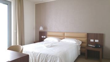Ein Hotelzimmer mit einem Bett, einem Schreibtisch, einem Stuhl, einer Lampe und einem Telefon.