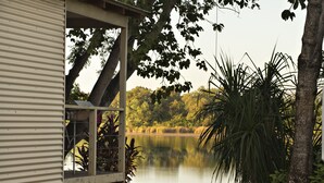 Un edificio con un amplio ventanal que da a un lago tranquilo, rodeado de abundante vegetación y árboles.