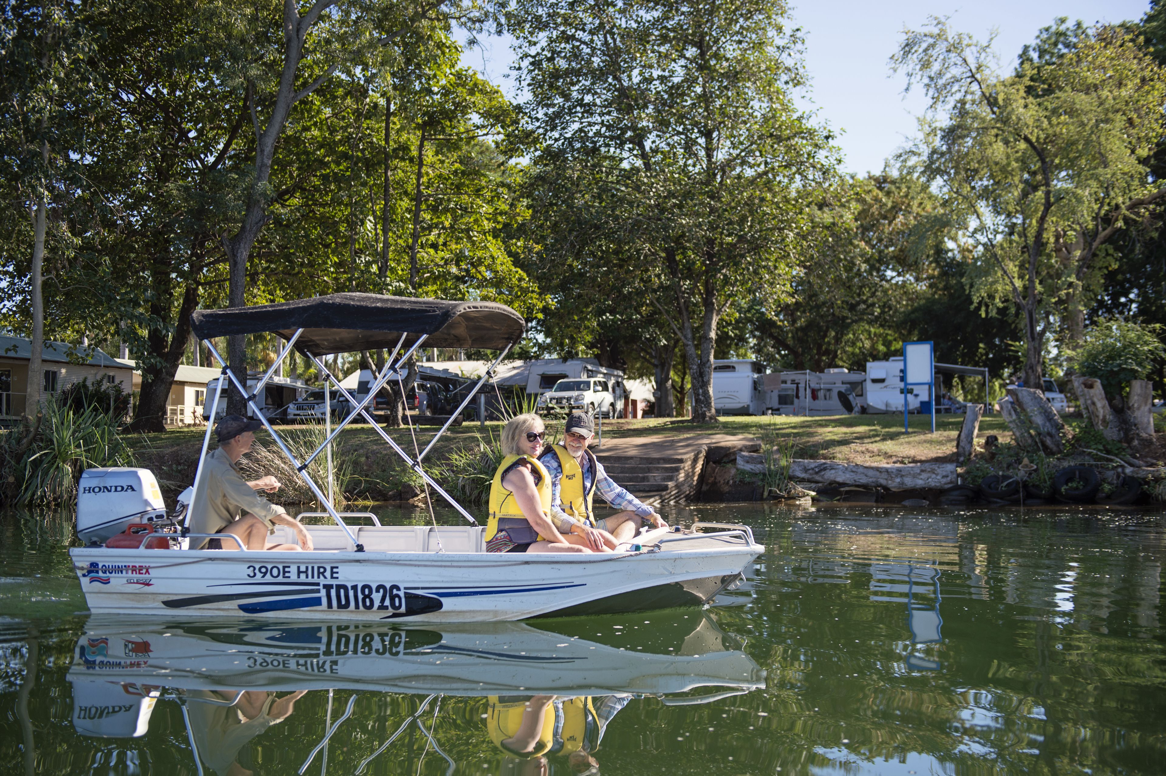 Un bateau avec deux personnes à bord, un auvent et un moteur.