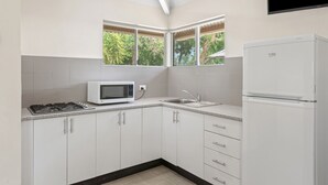 Una cocina moderna con gabinetes blancos, microondas, estufa y refrigerador.