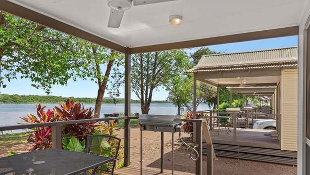 Terraza cubierta al aire libre con una parrilla, asientos y vista al lago.