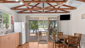 Una cocina moderna con vigas de madera, un comedor con mesa y sillas, y vistas al exterior.