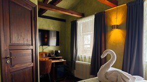 Une chambre à coucher comprenant un lit, un bureau, une chaise, un téléviseur et un radiateur.