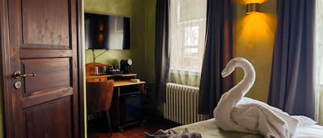 Un dormitorio con cama, escritorio, silla, televisor y radiador.