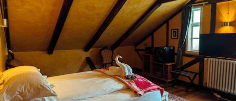 Un dormitorio con cama, una silla, un escritorio, un televisor y una ventana.