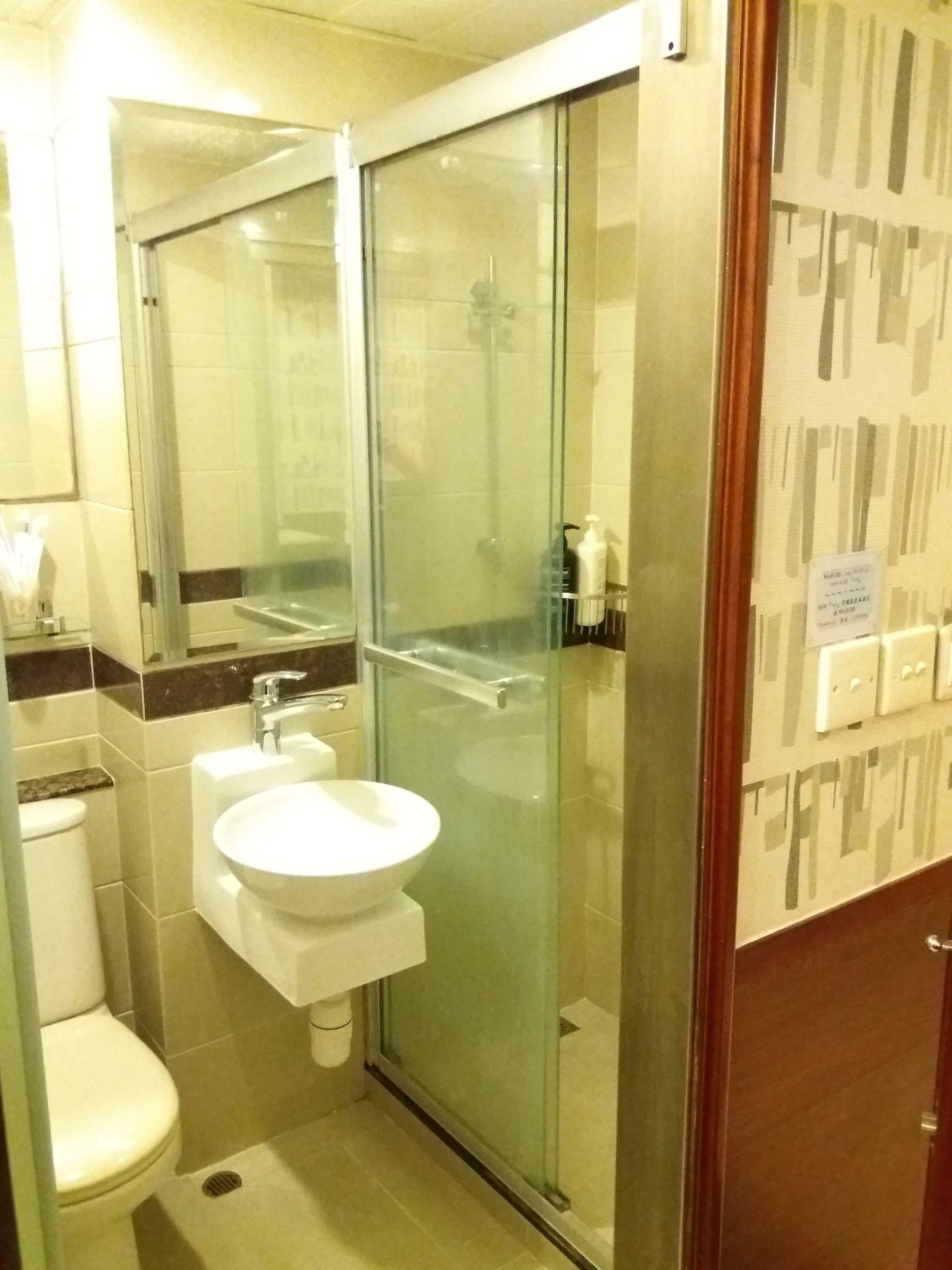 A bathroom with a glass shower enclosure, a sink, and a toilet.