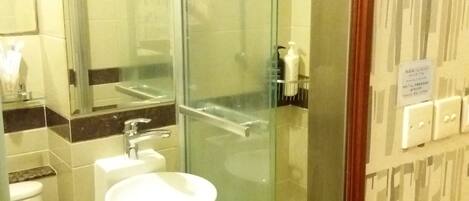 A bathroom with a glass shower enclosure, a sink, and a toilet.