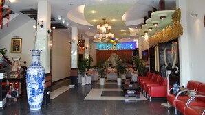 A hotel lobby with a large blue vase, red seating, and a neon sign reading "DAI LONG HOTEL". - Dai Long Hotel (Da Nang)