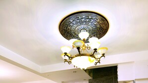 A lobby with wicker furniture, a dining area, a decorative ceiling light, and a stone wall with a sign. - Dai Long Hotel (Da Nang)