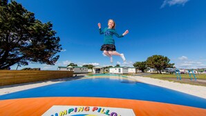 Un trampoline au design coloré, sur lequel on peut lire les mots « Jumping Pillow ».