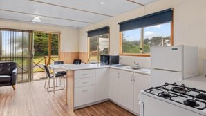 Une cuisine moderne équipée d’une cuisinière à gaz, de meubles blancs et d’un coin repas avec une table et des chaises.