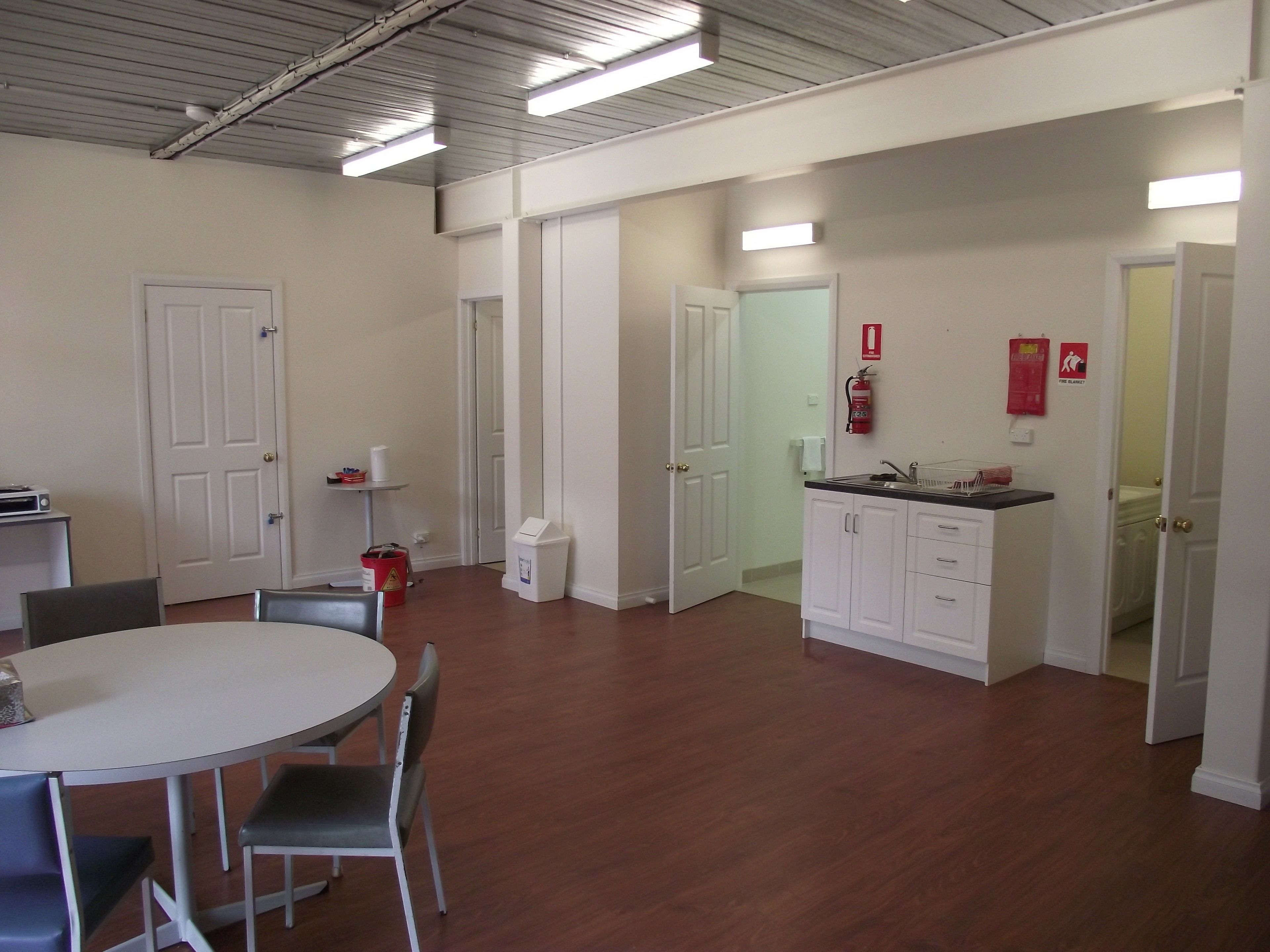 A spacious room with a dining table and chairs, a kitchenette, and white cabinets.