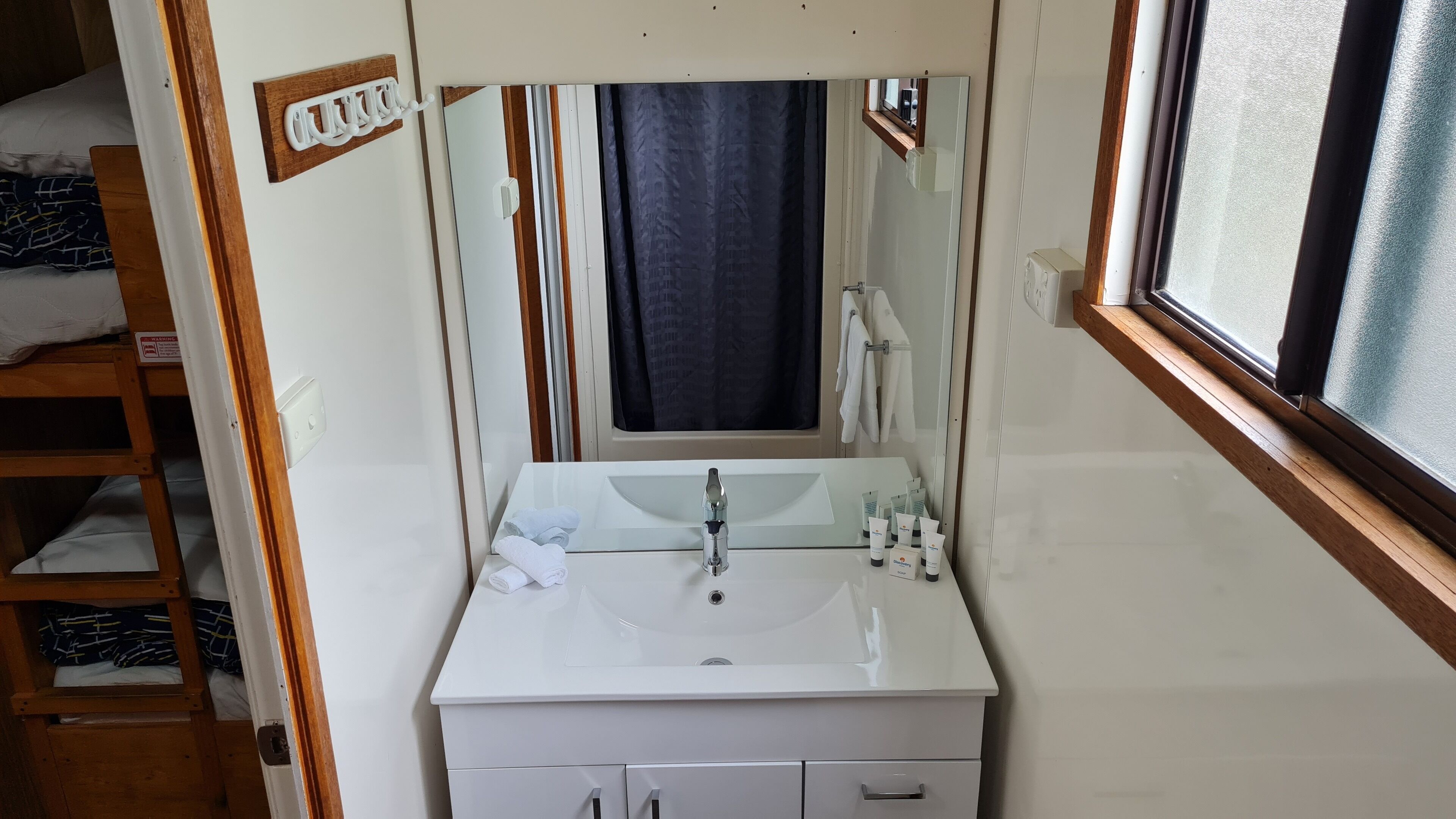 Un baño pequeño con lavamanos, espejo y almacenamiento de madera.
