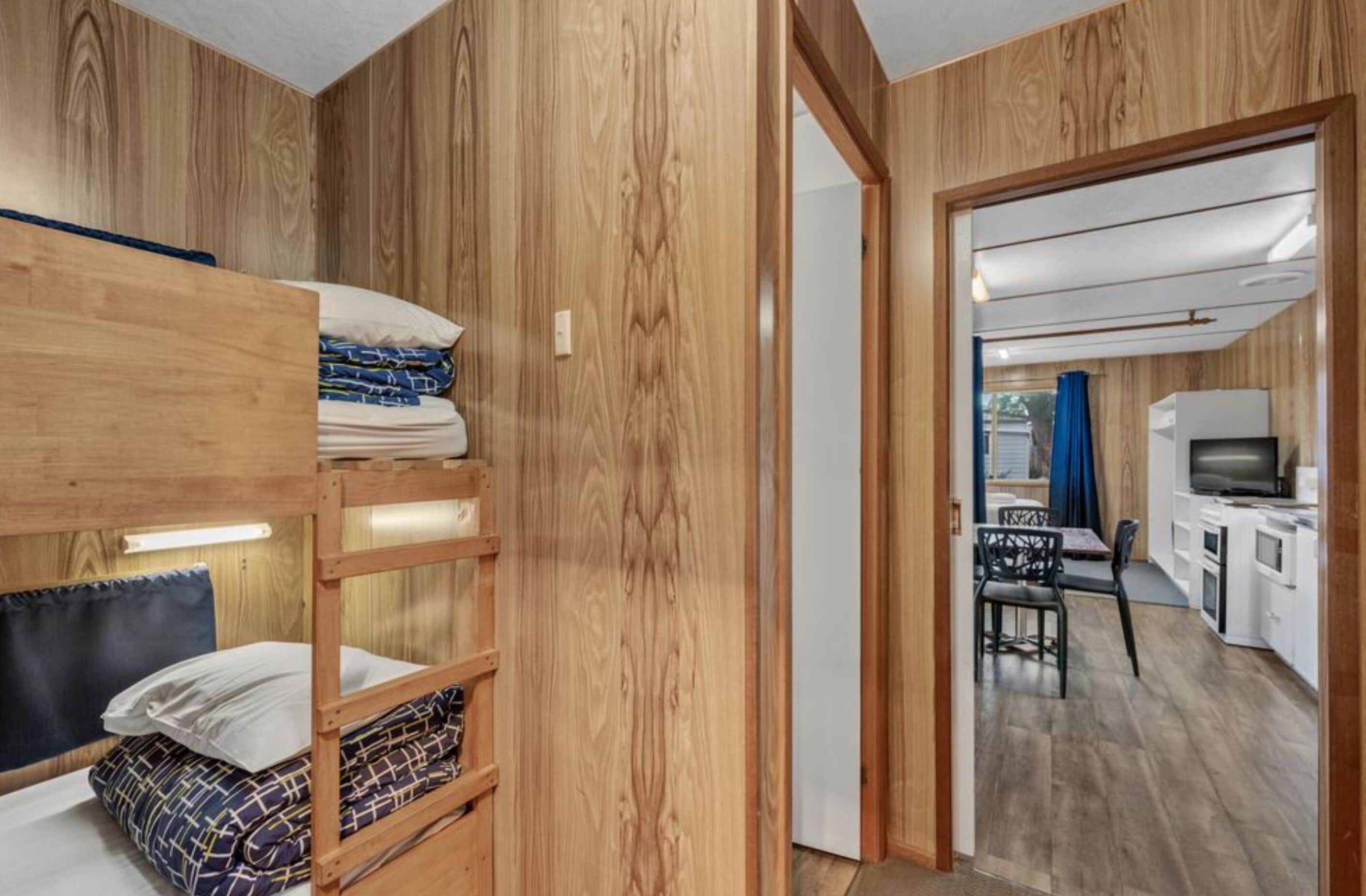 Ein Zimmer mit Holzboden, Etagenbetten, einer Küchenzeile und einem Essbereich.