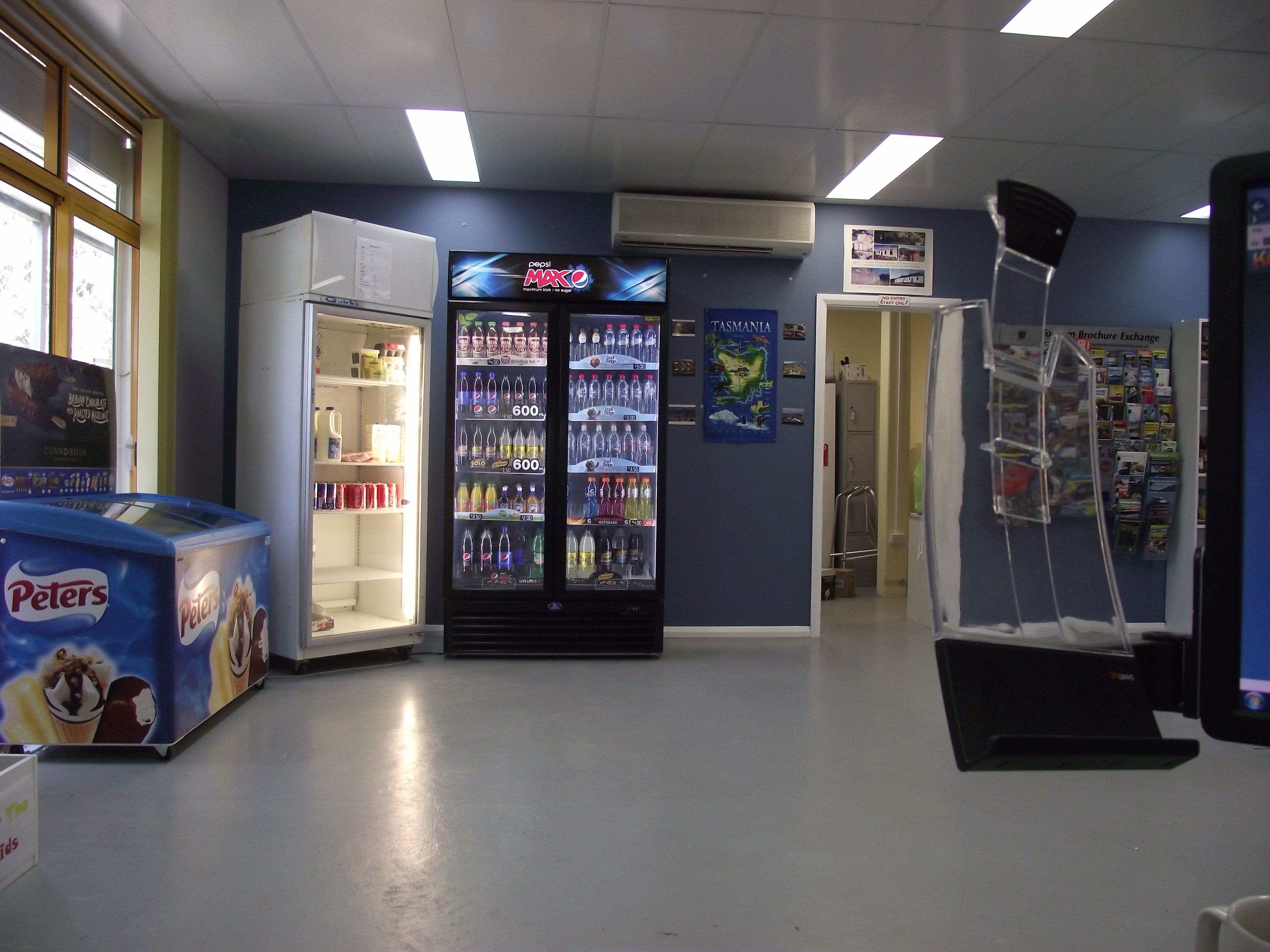 Een kamer met een automaat, een koelkast en een poster aan de muur.