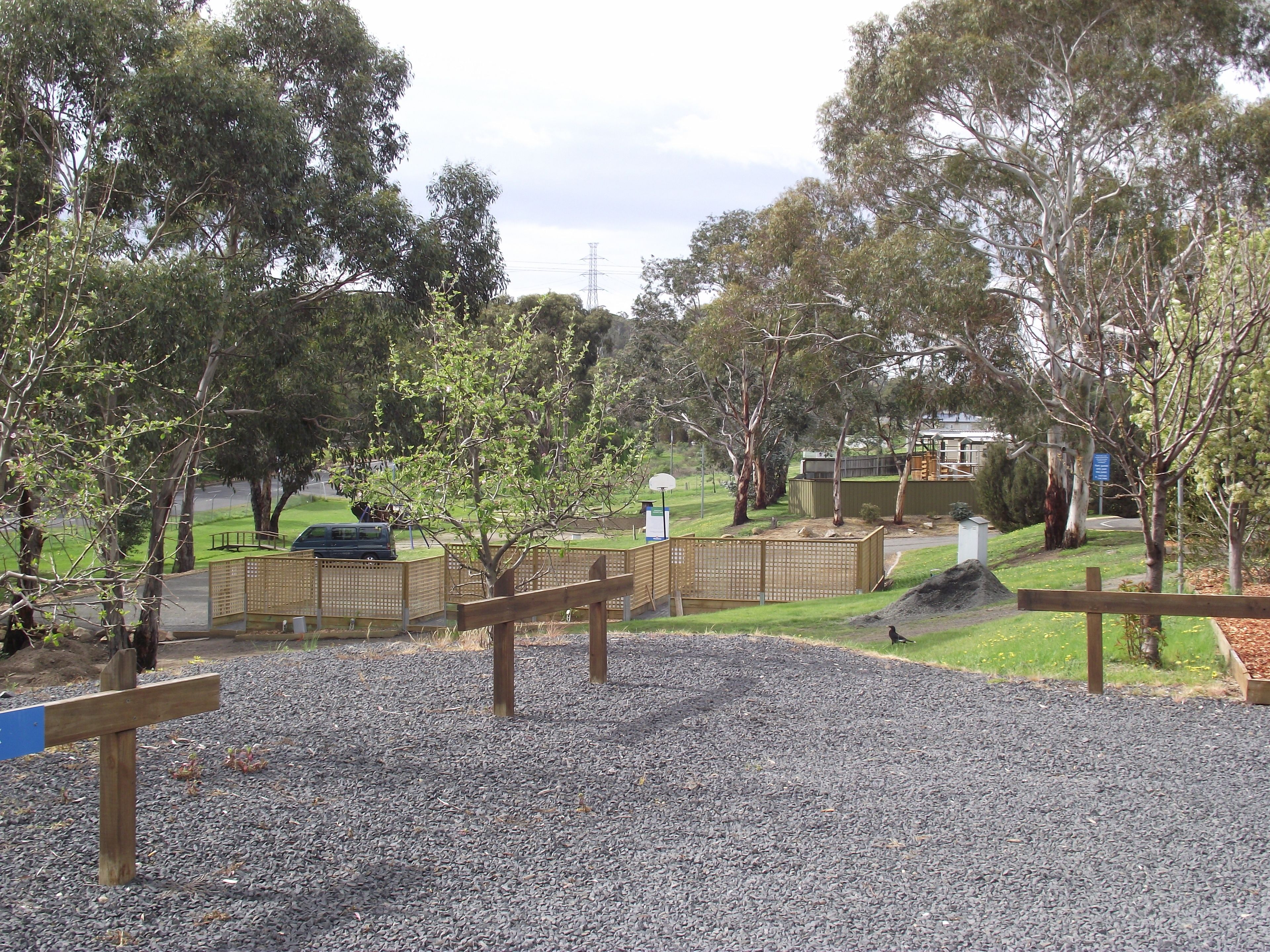 A park with a playground, trees, and a gravel path.