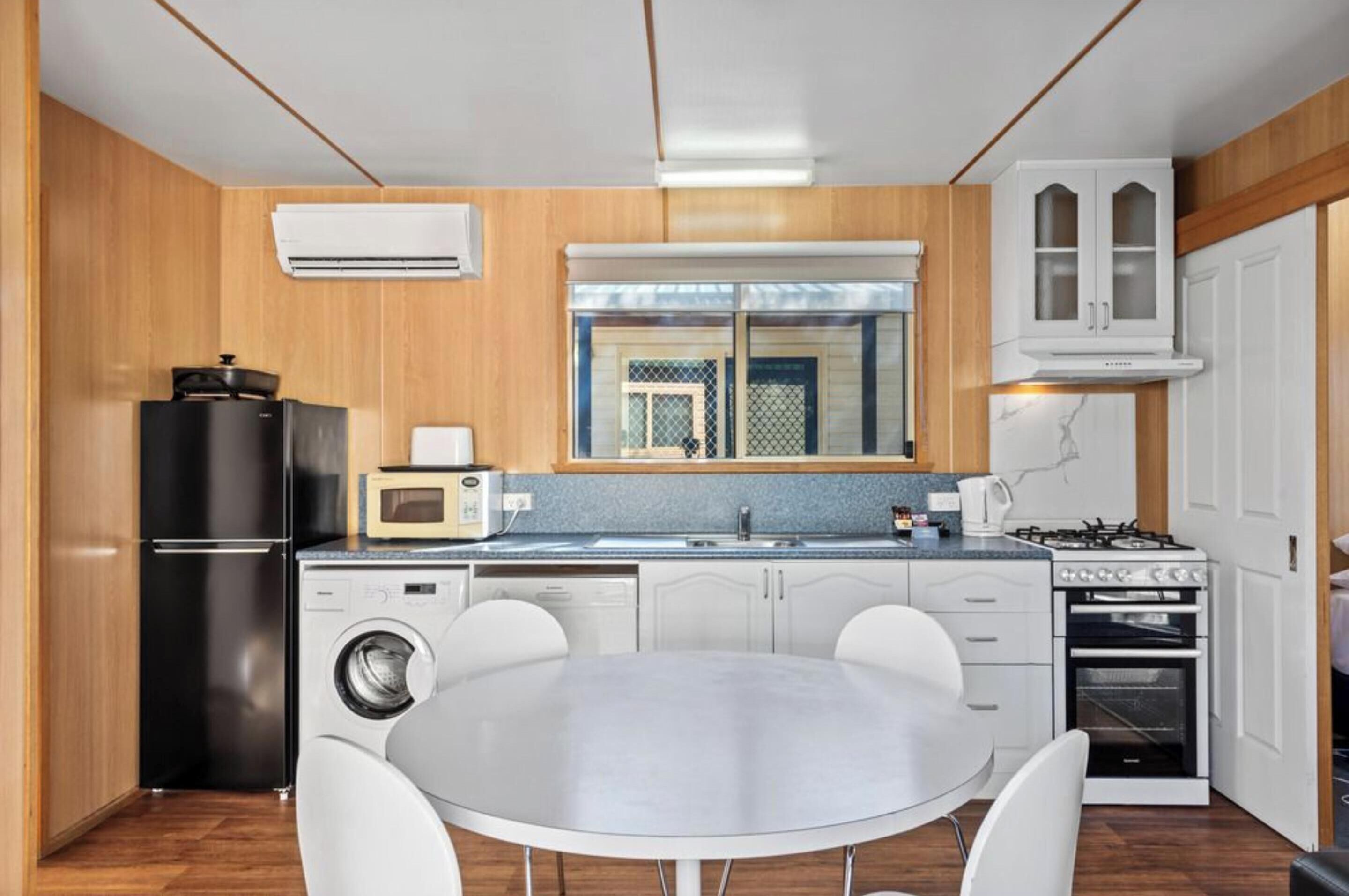 A compact kitchen with a washing machine, a microwave, a stove, and white cabinets.