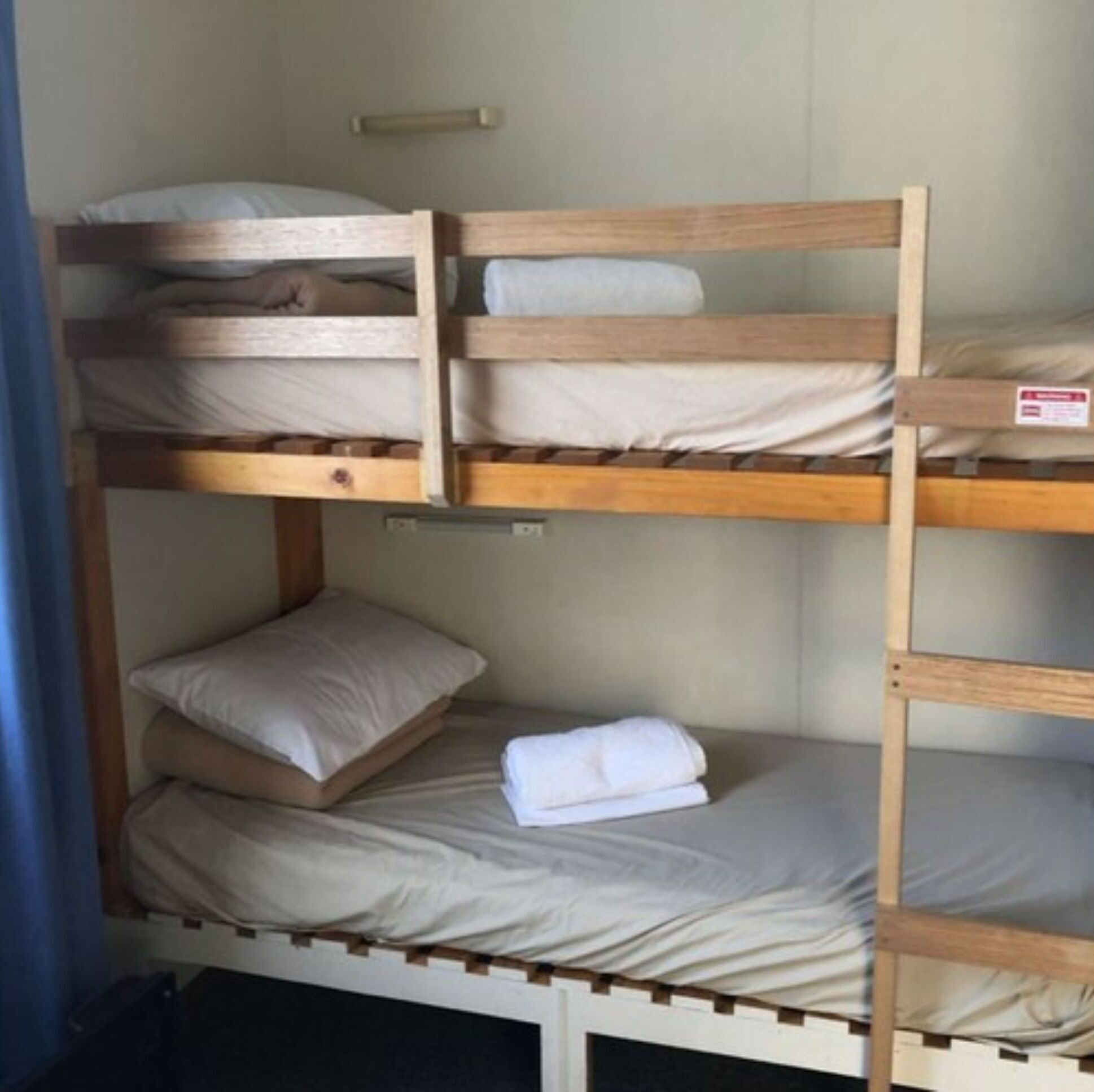 A bunk bed with two levels, each with a pillow and a folded towel.