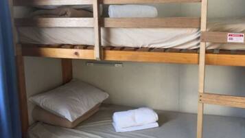A bunk bed with two levels, each with a pillow and a folded towel.